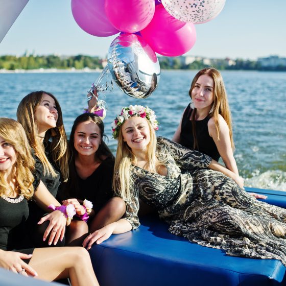 Five girls wear on black having fun at yacht against lake at hen party.